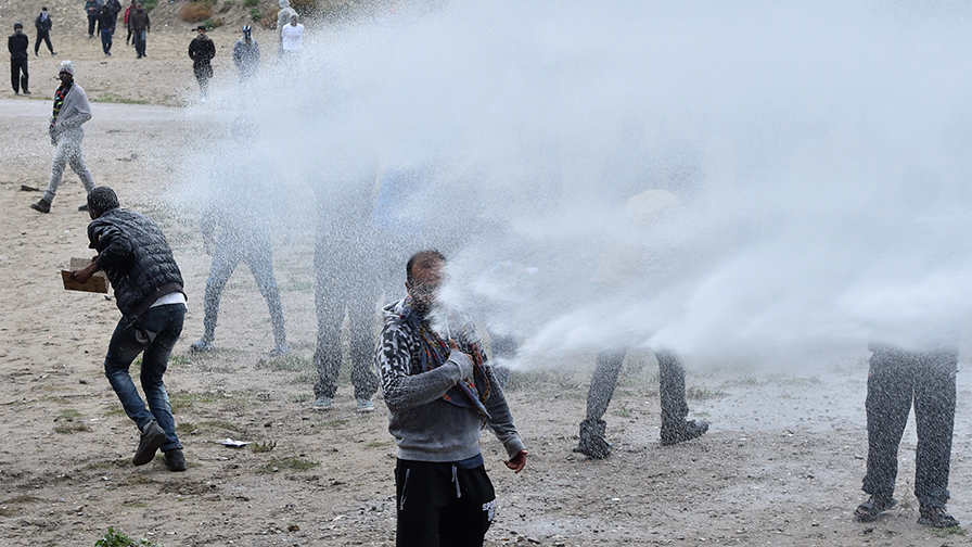 French police use water canons against participants during a march in support of migrants and refugees in the so-called 'Jungle' camp in the French northern port city of Calais on October 1, 2016. Between 7,000 and 10,000 migrants are currently living in the "Jungle", the launchpad for their attempts to stow away on lorries heading across the Channel to England. Rights groups have criticised the hardship and dangers facing the migrants living in the camp, particularly the hundreds of unaccompanied minors. / AFP PHOTO / PHILIPPE HUGUEN