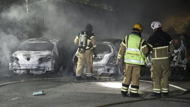 epa05489152 Swedish firemen stand next to extinguished car that were set on fire, in Malmo, Sweden, close to midnight on 15 August 2016. Media reports state that Swedish police is investigating a series of vehicle burnings in various Malmo neighborhoods but was so far unable to get hold of any perpetrators. EPA/JOHAN NILSSON SWEDEN OUT