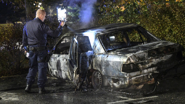 A police officer checks a burned out car at Karleksvagen in Burlov, near Malmo, Sweden, Tuesday Sept. 20, 2016. Police in Malmo say a recent surge in car fires, with about 30 cars set ablaze since Friday, could be linked to a crackdown on gangland crime, after police arrested three men with suspected links to organised crime involving guns and explosives. (Johan Nilsson / TT via AP)
