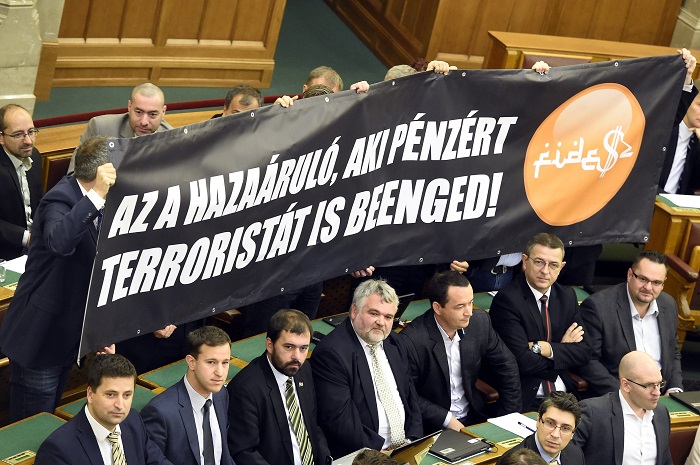 Budapest, 2016. november 8. Jobbikos képviselõk Az a hazaáruló, aki pénzért terroristát is beenged! feliratú molinót tartanak az alaptörvény hetedik módosításáról szóló szavazás alatt az Országgyûlés plenáris ülésén 2016. november 8-án. 131 képviselõ szavazott igennel, 3 nemmel, így nem kapta meg a kétharmados támogatást Orbán Viktor miniszterelnök alkotmánymódosítási javaslata, amely kimondta volna, hogy Magyarországra idegen népesség nem telepíthetõ be. MTI Fotó: Kovács Tamás