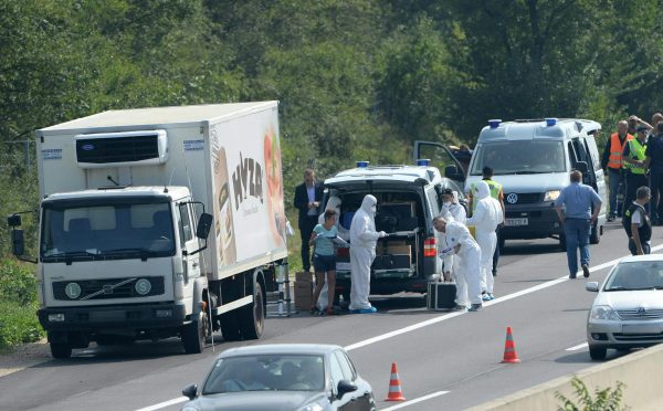 Védõruhába öltözött rendõrök egy teherautó mögött az A4-es autópályán Pandorf közelében 2015. augusztus 27-én. A teherautóban menekültek holttestére bukkantak. Egyes sajtóértesülések szerint akár az ötvenet is elérheti a halottak száma. (MTI/EPA/Roland Schlager)